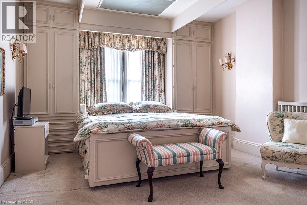 Recessed window with decorative drapes, flanked by built-in cabinetry featuring paneled doors and drawer storage - 370 Hess Street S, Hamilton, ON - Indoor Photo Showing Bedroom