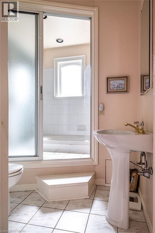 Bathroom featuring a pedestal sink with brass-finish faucet, tile flooring, and a sliding frosted glass shower enclosure - 370 Hess Street S, Hamilton, ON - Indoor Photo Showing Bathroom