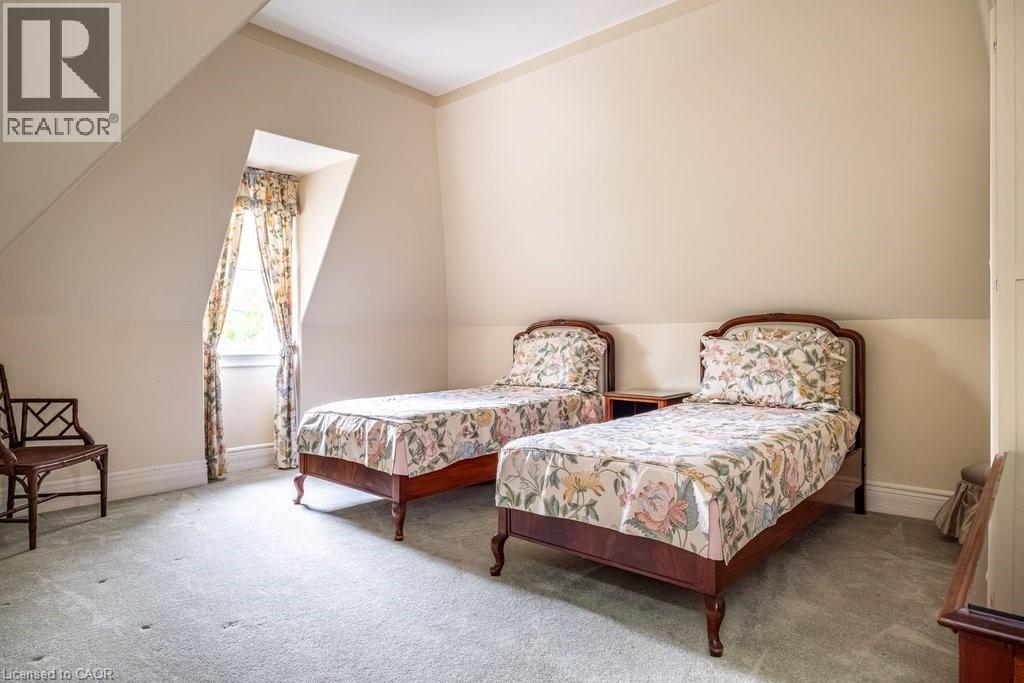 Sloped ceiling room featuring a window with patterned drapes, light-toned walls, and grey carpeting - 370 Hess Street S, Hamilton, ON - Indoor Photo Showing Bedroom