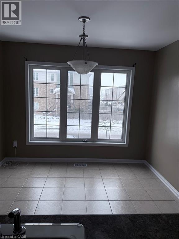 Spacious interior featuring a large multi-pane window, ceramic tile flooring, a semi-flush mount light fixture, and a dark countertop - 50 Emick Drive, Ancaster, ON - Indoor Photo Showing Other Room
