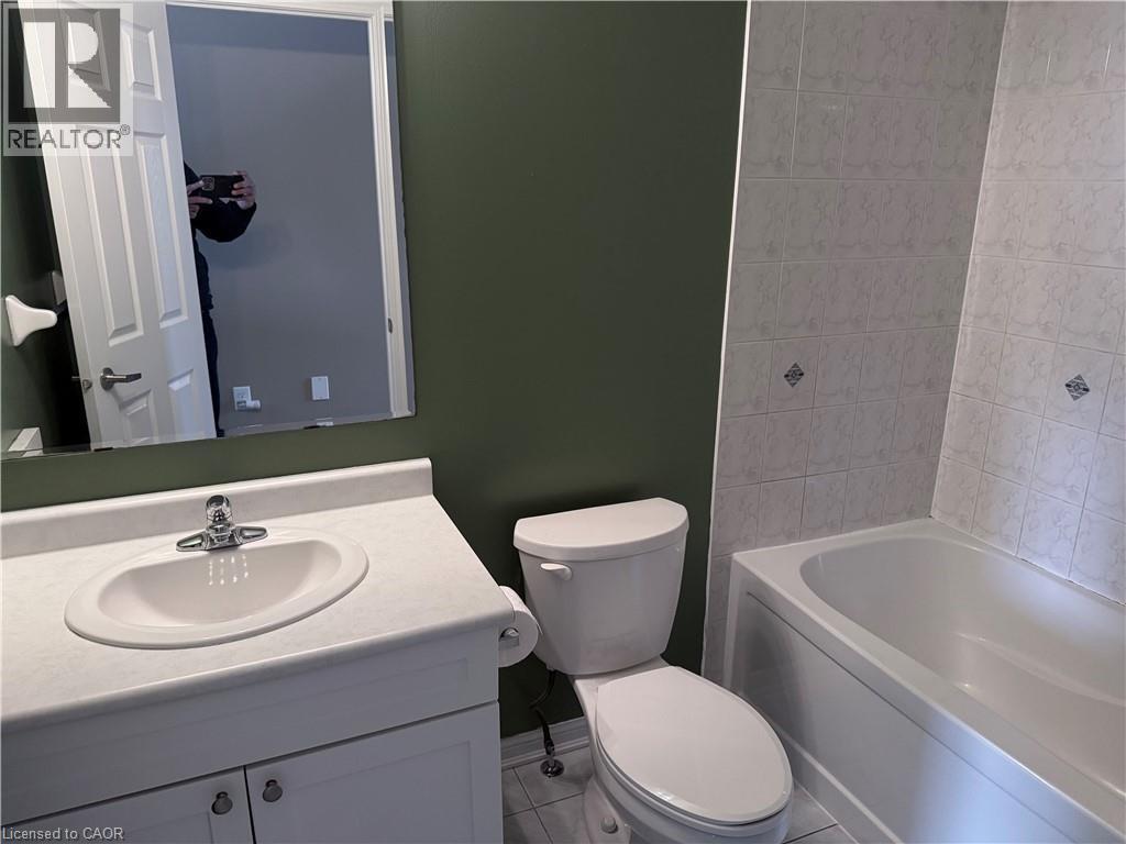 Bathroom featuring a white vanity with an integrated sink, chrome faucet, wall-mounted mirror, and a white toilet - 50 Emick Drive, Ancaster, ON - Indoor Photo Showing Bathroom