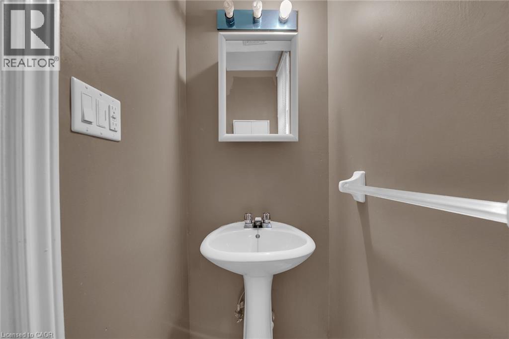 Pedestal sink with chrome faucet set beneath a medicine cabinet and vanity light fixture - 738 King Street W, Hamilton, ON - Indoor Photo Showing Bathroom