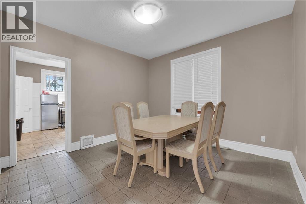 Dining area featuring neutral wall paint, tiled flooring, a window with horizontal blinds, and a ceiling-mounted light fixture - 738 King Street W, Hamilton, ON - Indoor Photo Showing Dining Room
