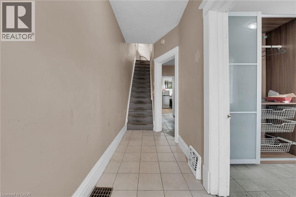 Foyer featuring neutral wall tones, white baseboards, and square tile flooring - 738 King Street W, Hamilton, ON - Indoor Photo Showing Other Room