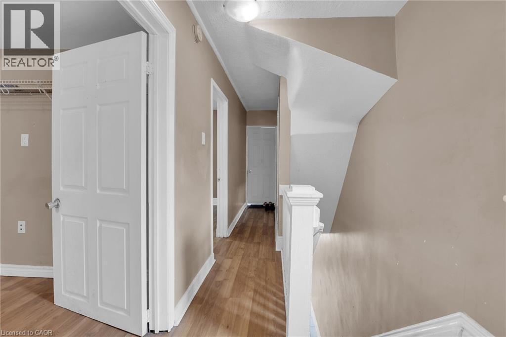 Hallway featuring wood-finish flooring, light tan wall paint, and white trim - 738 King Street W, Hamilton, ON - Indoor Photo Showing Other Room