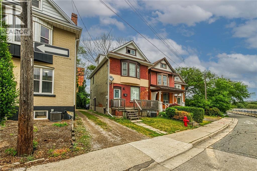 Brick facade residence featuring a covered front porch with wood railings and steps - 738 King Street W, Hamilton, ON - Outdoor With Facade