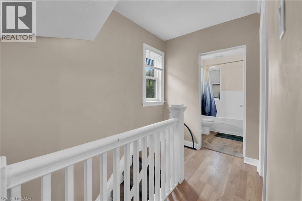 Upper landing featuring light-toned walls, wood-finish flooring, and white painted railings - 738 King Street W, Hamilton, ON - Indoor Photo Showing Other Room