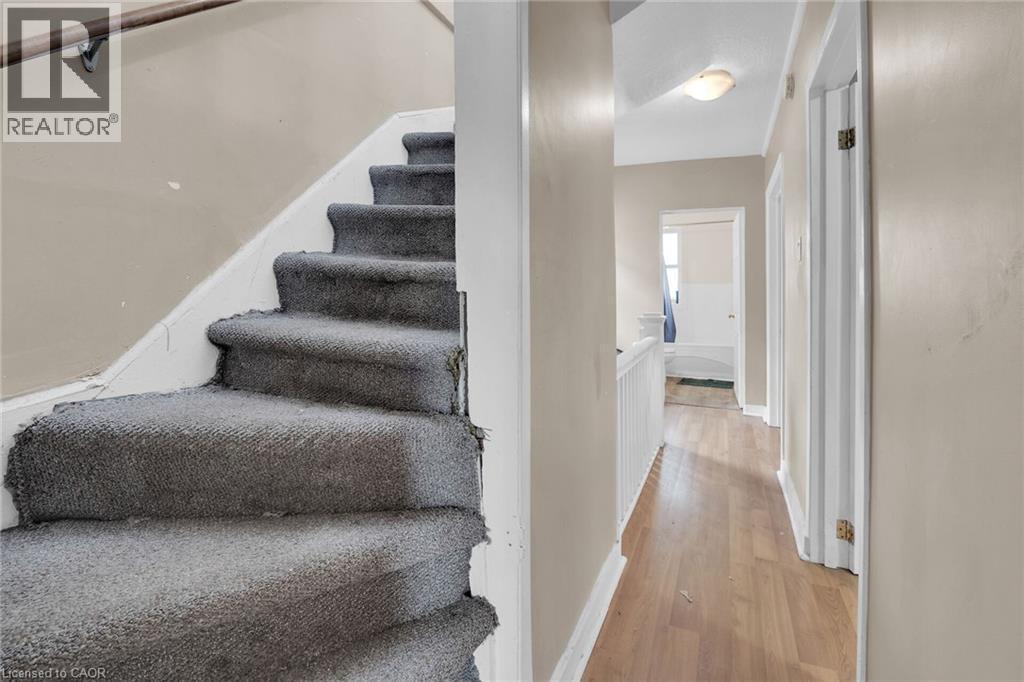 Staircase featuring grey carpeting and a wooden handrail - 738 King Street W, Hamilton, ON - Indoor Photo Showing Other Room