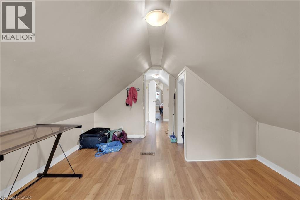 Attic space featuring sloped ceilings, wood-finish flooring, and light neutral wall tones - 738 King Street W, Hamilton, ON - Indoor Photo Showing Other Room