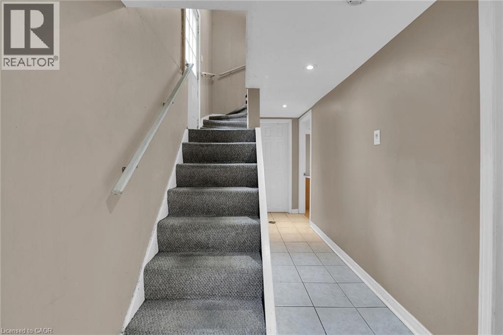Carpeted staircase with an aluminum handrail, leading to an upper level with natural light from a window - 738 King Street W, Hamilton, ON - Indoor Photo Showing Other Room