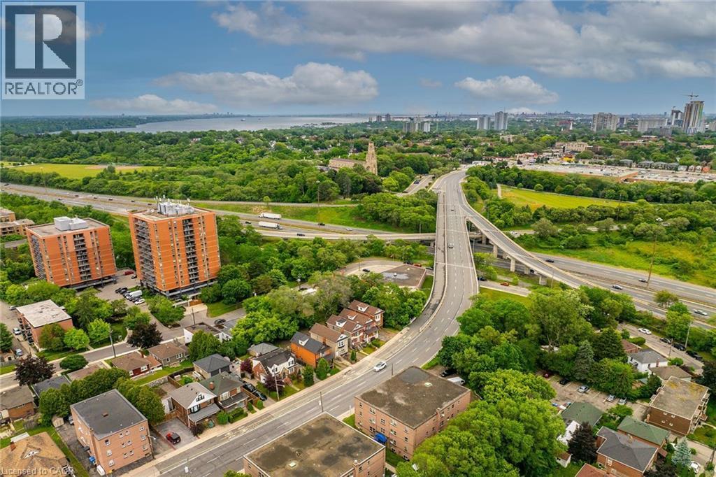 Aerial perspective showcasing an expansive urban landscape with abundant greenery, prominent roadways, and residential structures - 738 King Street W, Hamilton, ON - Outdoor With View
