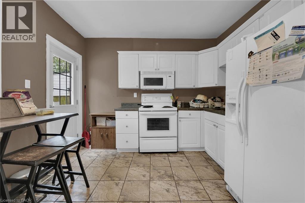 Kitchen featuring white cabinetry, dark countertops, and tile flooring - 738 King Street W, Hamilton, ON - Indoor Photo Showing Kitchen