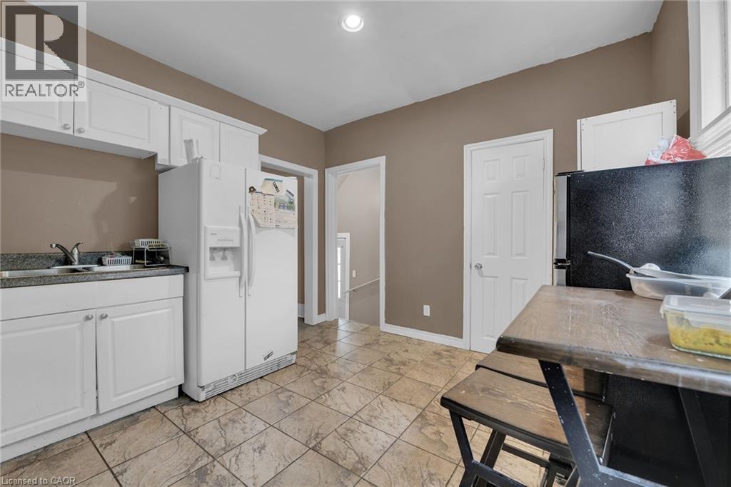 Kitchen featuring white cabinetry, a stainless steel sink, tiled flooring, and neutral wall paint - 738 King Street W, Hamilton, ON - Indoor
