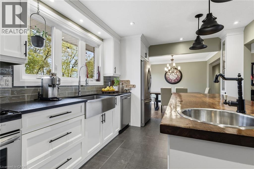 Modern kitchen featuring white cabinetry, black countertops, and a subway tile backsplash - 2116 Binbrook Road E, Hamilton, ON - Indoor Photo Showing Kitchen With Double Sink