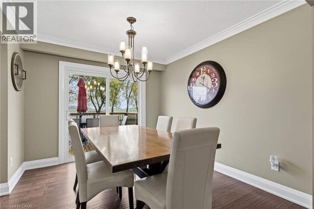 Dining area featuring wood-finish flooring, crown molding, a multi-arm chandelier, and sliding glass doors leading to an outdoor deck - 2116 Binbrook Road E, Hamilton, ON - Indoor Photo Showing Dining Room