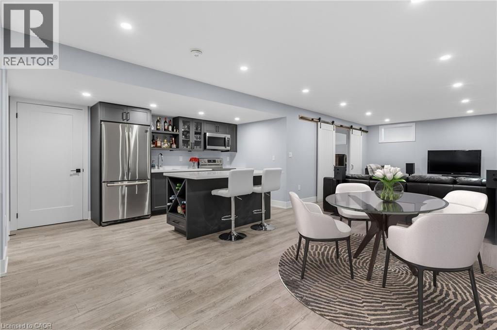Open-concept recreational space featuring a fully equipped wet bar with stainless steel appliances, a center island with seating, recessed lighting, and wood-finish flooring - 2116 Binbrook Road E, Hamilton, ON - Indoor Photo Showing Dining Room