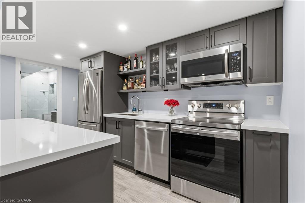 Contemporary kitchen featuring grey cabinetry, stainless steel appliances, a white solid-surface countertop, and light wood-finish flooring - 2116 Binbrook Road E, Hamilton, ON - Indoor Photo Showing Kitchen With Upgraded Kitchen