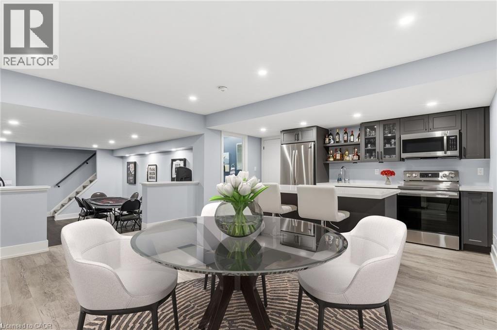 Lower level entertainment area featuring wood-finish flooring, recessed lighting, and a built-in wet bar with glass-front cabinetry and stainless steel appliances - 2116 Binbrook Road E, Hamilton, ON - Indoor