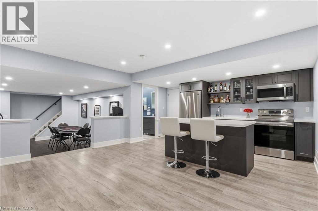 Open-concept basement featuring wood-finish flooring, recessed lighting, and a contemporary wet bar with stainless steel appliances - 2116 Binbrook Road E, Hamilton, ON - Indoor Photo Showing Kitchen
