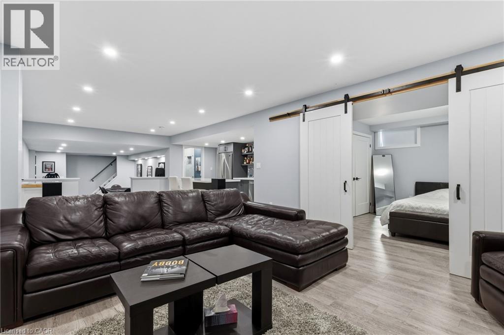 Finished lower level featuring recessed lighting, wood-finish flooring, white barn doors with black hardware, a built-in wet bar, and an open-concept layout - 2116 Binbrook Road E, Hamilton, ON - Indoor Photo Showing Living Room