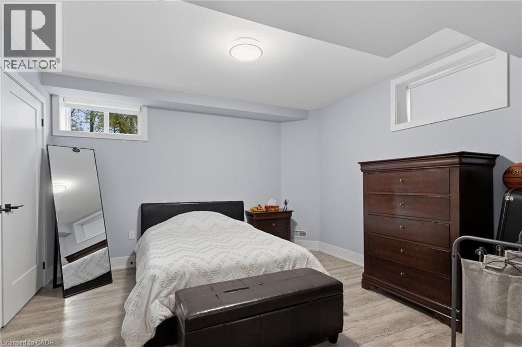 Well-appointed room featuring two windows, light wood-finish flooring, and a modern flush-mount ceiling light - 2116 Binbrook Road E, Hamilton, ON - Indoor Photo Showing Bedroom