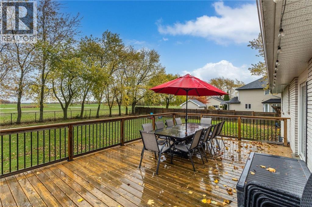 Expansive wood-finish deck with black spindle railing, featuring string lighting and direct access to the home's exterior - 2116 Binbrook Road E, Hamilton, ON - Outdoor With Deck Patio Veranda
