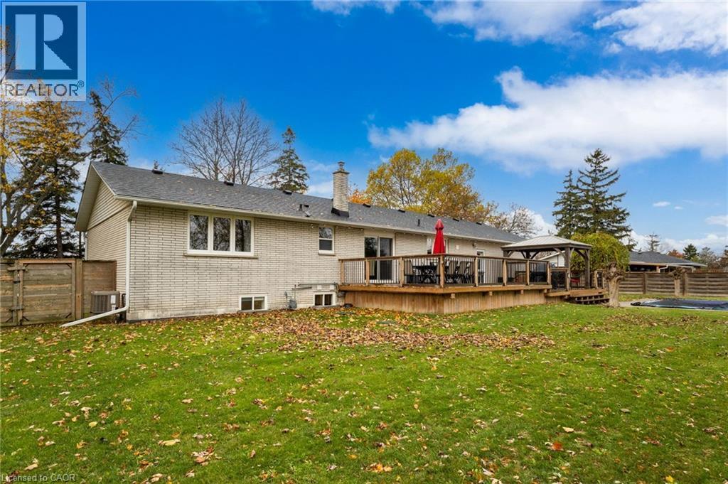 Expansive backyard featuring a large wood-finish deck with railing, a built-in gazebo, a light-colored brick exterior, and a privacy fence - 2116 Binbrook Road E, Hamilton, ON - Outdoor With Deck Patio Veranda