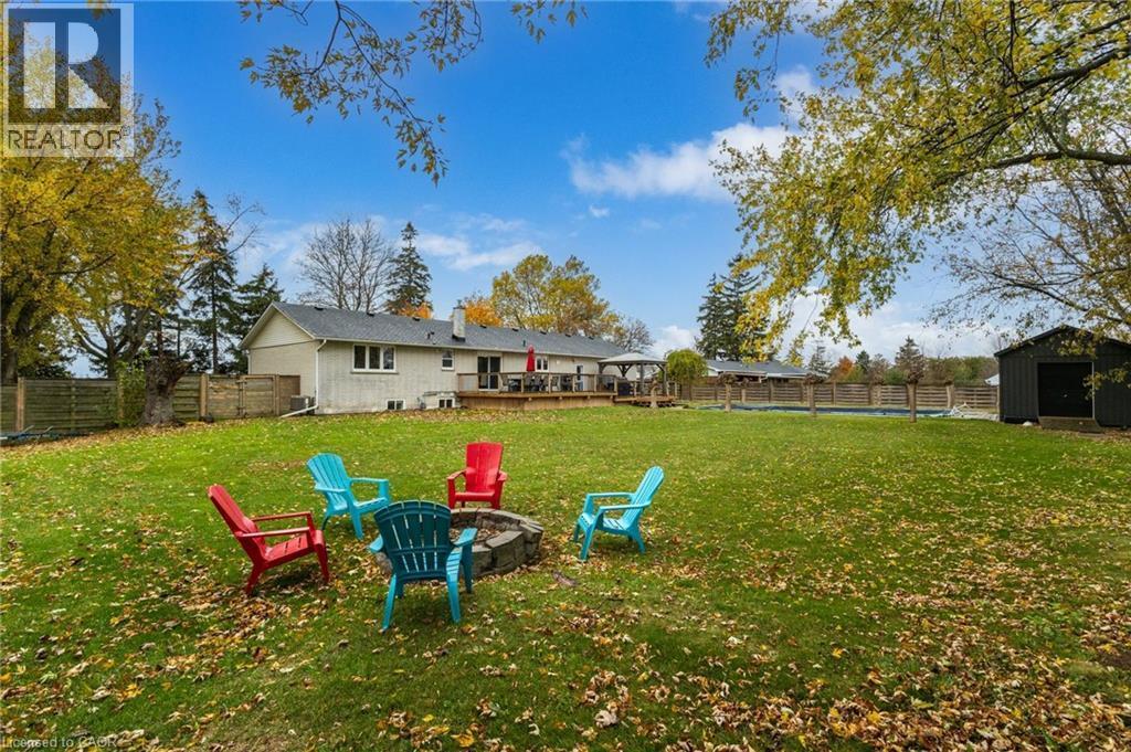 Expansive lawn with a built-in fire pit, privacy fencing, and mature trees - 2116 Binbrook Road E, Hamilton, ON - Outdoor With Backyard