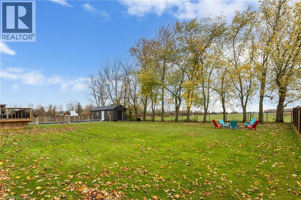 Expansive backyard featuring a manicured lawn, established trees, a dark-toned shed, a multi-level deck, and a fenced pool area - 2116 Binbrook Road E, Hamilton, ON - Outdoor