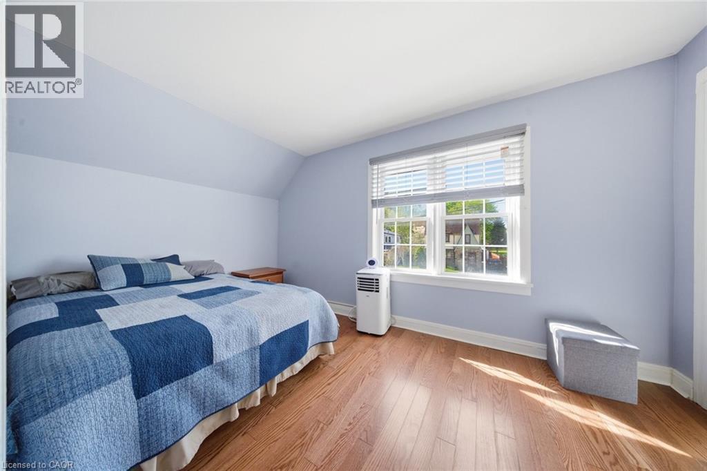 Bedroom featuring wood-finish flooring, a window with horizontal blinds, and sloped ceiling details - 401 West Street, Simcoe, ON - Indoor Photo Showing Bedroom