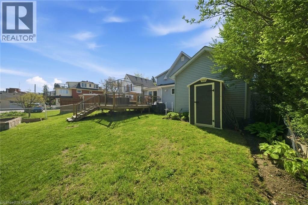 Expansive backyard featuring a manicured lawn, a multi-level wood deck with stairs, a built-in storage shed, and established perimeter landscaping - 401 West Street, Simcoe, ON - Outdoor
