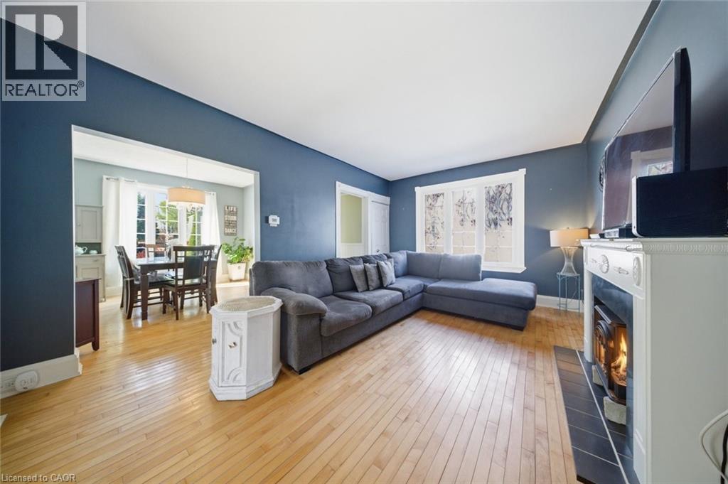 Spacious living area featuring light wood-finish flooring, a white mantel, and a dark tile hearth - 401 West Street, Simcoe, ON - Indoor Photo Showing Living Room With Fireplace