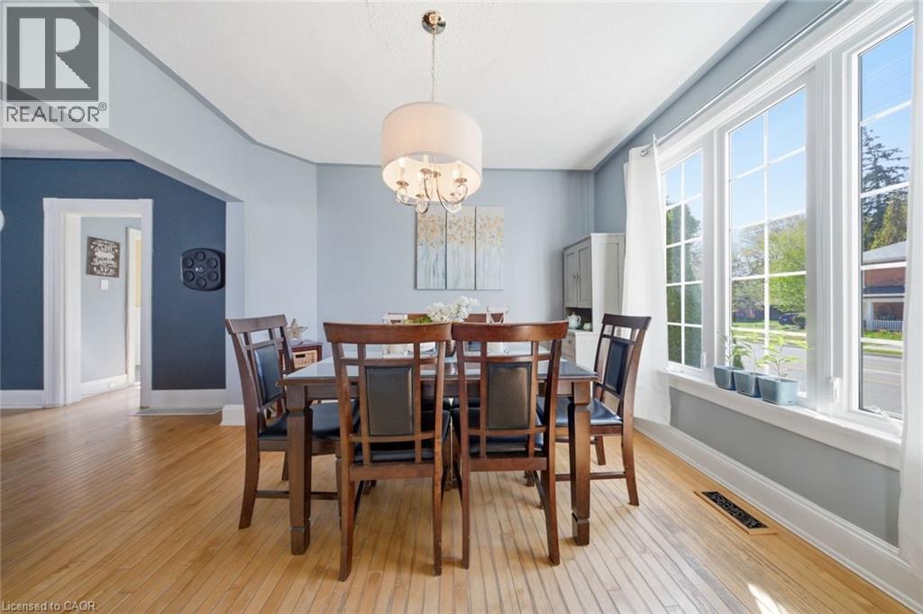 Dining area featuring wood-finish flooring, a contemporary drum pendant light fixture, and a large multi-pane window - 401 West Street, Simcoe, ON - Indoor Photo Showing Dining Room