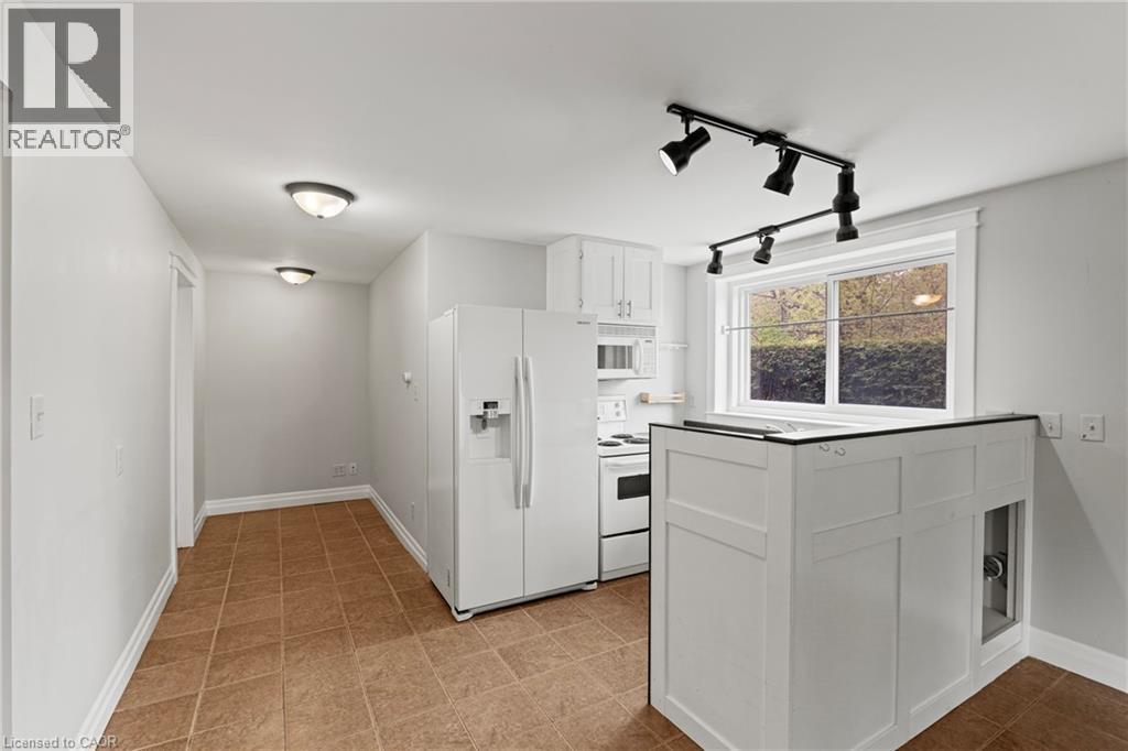 Kitchen featuring white cabinetry, white appliances, track lighting, and a window with exterior shrubbery - 3 San Pedro Drive, Hamilton, ON - Indoor Photo Showing Other Room