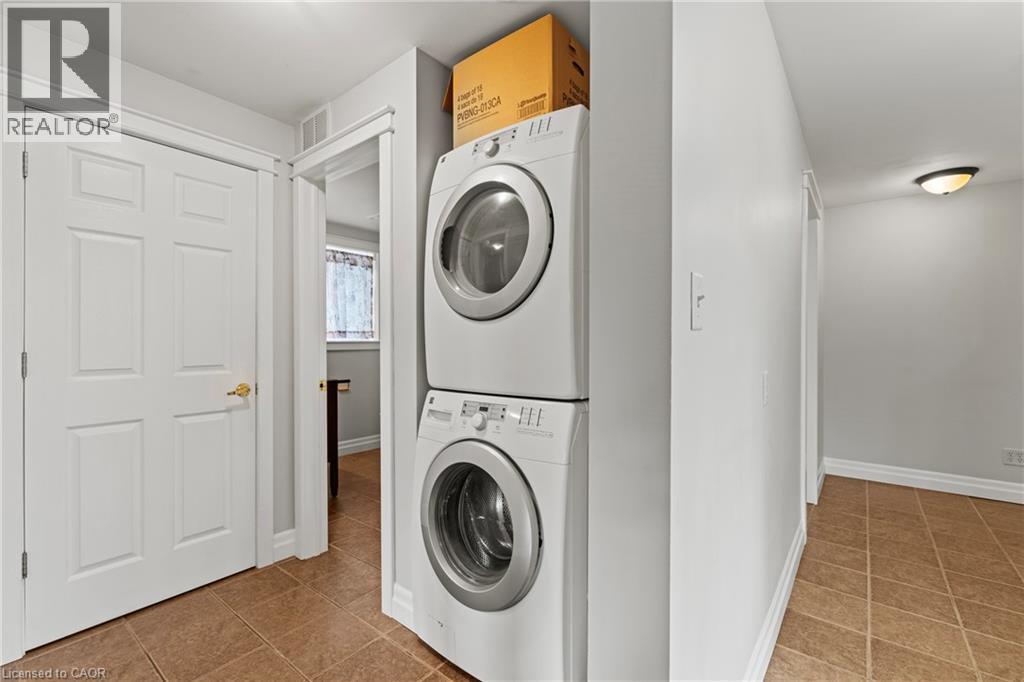 Dedicated laundry area featuring a stacked washer and dryer unit, neutral wall paint, and tile flooring - 3 San Pedro Drive, Hamilton, ON - Indoor Photo Showing Laundry Room