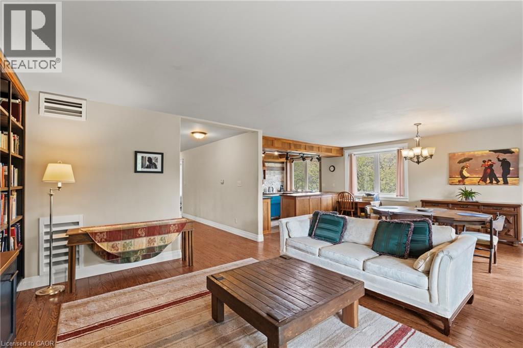 Open-concept living area featuring wood-finish flooring, built-in shelving, a kitchen pass-through, and a dining area with an overhead chandelier - 3 San Pedro Drive, Hamilton, ON - Indoor Photo Showing Living Room