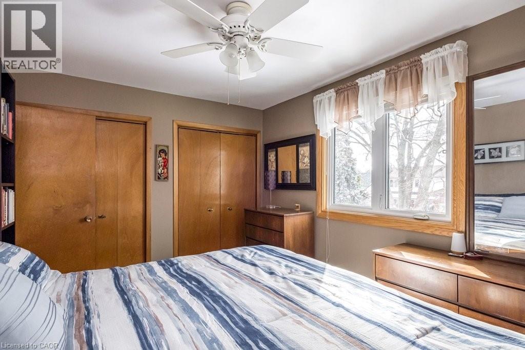 Bedroom featuring a large window, dual sliding closet doors, a ceiling fan with integrated lighting, and a neutral wall color - 19 Chateau Court, Hamilton, ON - Indoor Photo Showing Bedroom