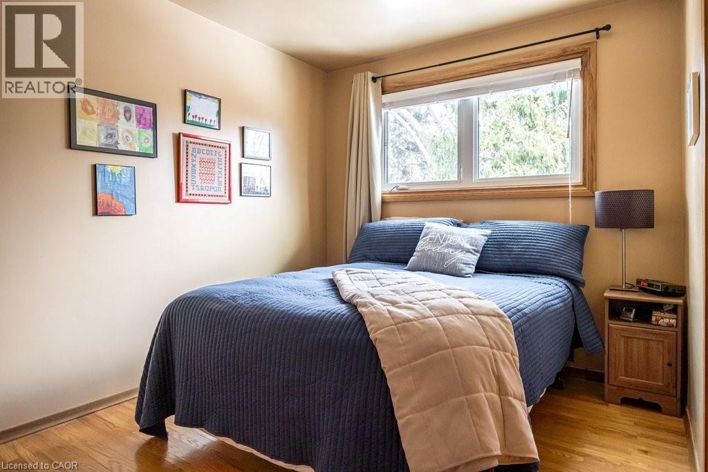 Bedroom featuring wood-finish flooring, a window with wood trim, and neutral painted walls - 19 Chateau Court, Hamilton, ON - Indoor Photo Showing Bedroom
