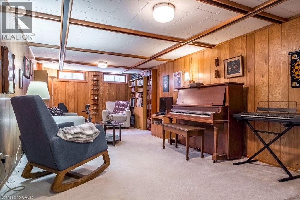 Finished room featuring wood-panel walls, light-colored carpeting, a drop ceiling with exposed wood beams, and built-in shelving - 19 Chateau Court, Hamilton, ON - Indoor Photo Showing Other Room