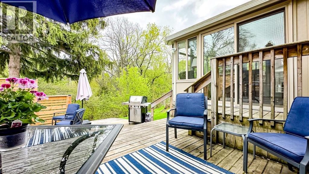 Multi-level wood deck featuring a built-in railing, direct access to the interior via sliding glass doors, and a natural tree-lined backdrop - 19 Chateau Court, Hamilton, ON - Outdoor With Deck Patio Veranda With Exterior