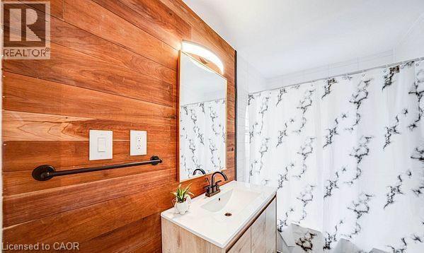 Wood-finish accent wall with integrated mirror and vanity lighting - 43 Adair Avenue S, Hamilton, ON - Indoor Photo Showing Bathroom