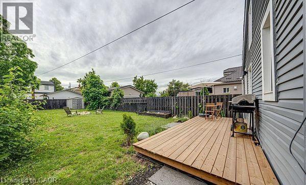 Expansive backyard featuring a natural wood deck, a manicured lawn, and a dark-stained wood fence - 43 Adair Avenue S, Hamilton, ON - Outdoor With Deck Patio Veranda