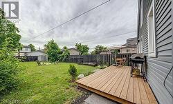 Expansive backyard featuring a natural wood deck, a manicured lawn, and a dark-stained wood fence -