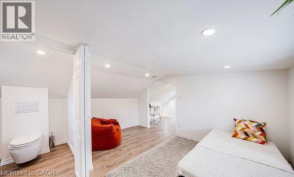 Attic space featuring wood-finish flooring, recessed lighting, and a partial wall with a built-in toilet - 43 Adair Avenue S, Hamilton, ON - Indoor Photo Showing Other Room
