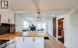 Kitchen featuring white shaker cabinetry with matte black hardware, wood-finish countertops, and a black tile backsplash -