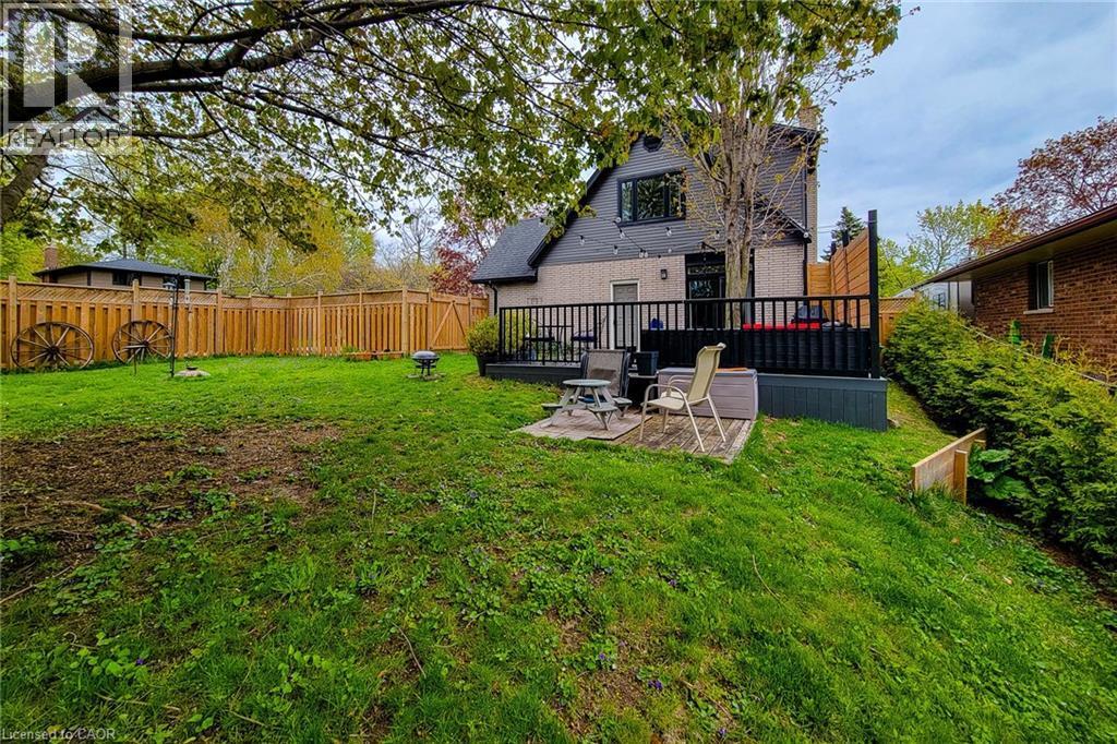 Expansive backyard featuring a wood fence, mature tree, and a multi-level deck with black railings - 49 Ashwood Drive, Cambridge, ON - Outdoor With Deck Patio Veranda