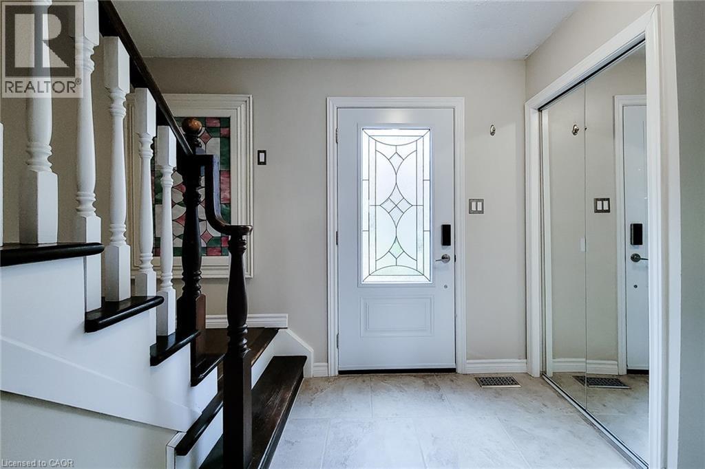 Entryway featuring a white door with decorative glass, light-toned tile flooring, and a mirrored closet - 49 Ashwood Drive, Cambridge, ON - Indoor Photo Showing Other Room