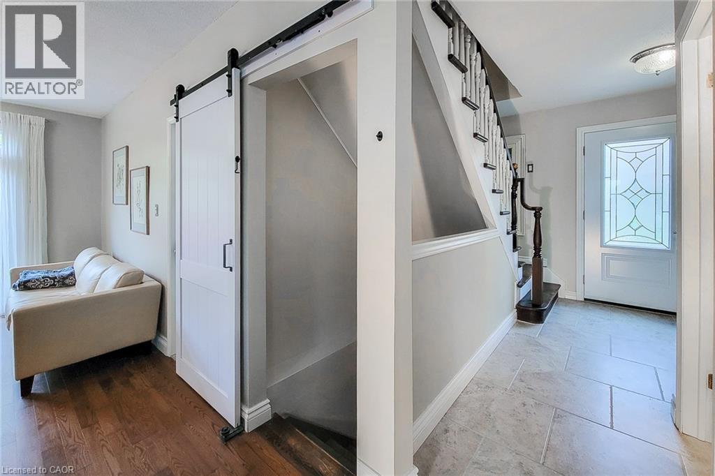 Entryway featuring a decorative glass front door, staircase with white spindles and dark wood handrail, and large format tile flooring - 49 Ashwood Drive, Cambridge, ON - Indoor Photo Showing Other Room