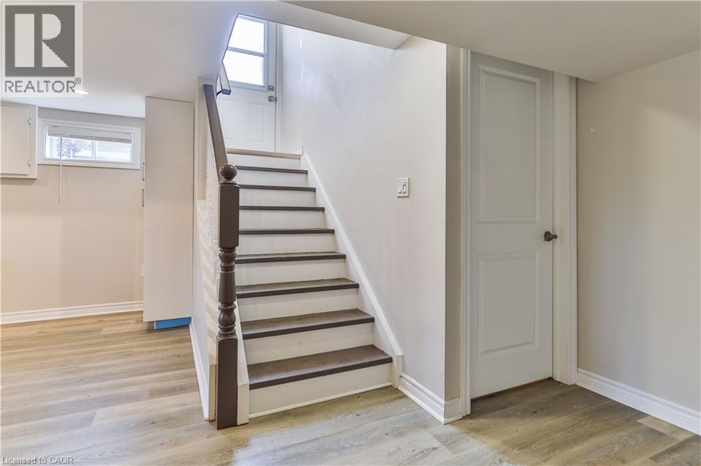 Staircase featuring dark wood newel post and railings, white risers, and dark treads - 38 Dunkirk Drive Unit# B, Hamilton, ON - Indoor Photo Showing Other Room