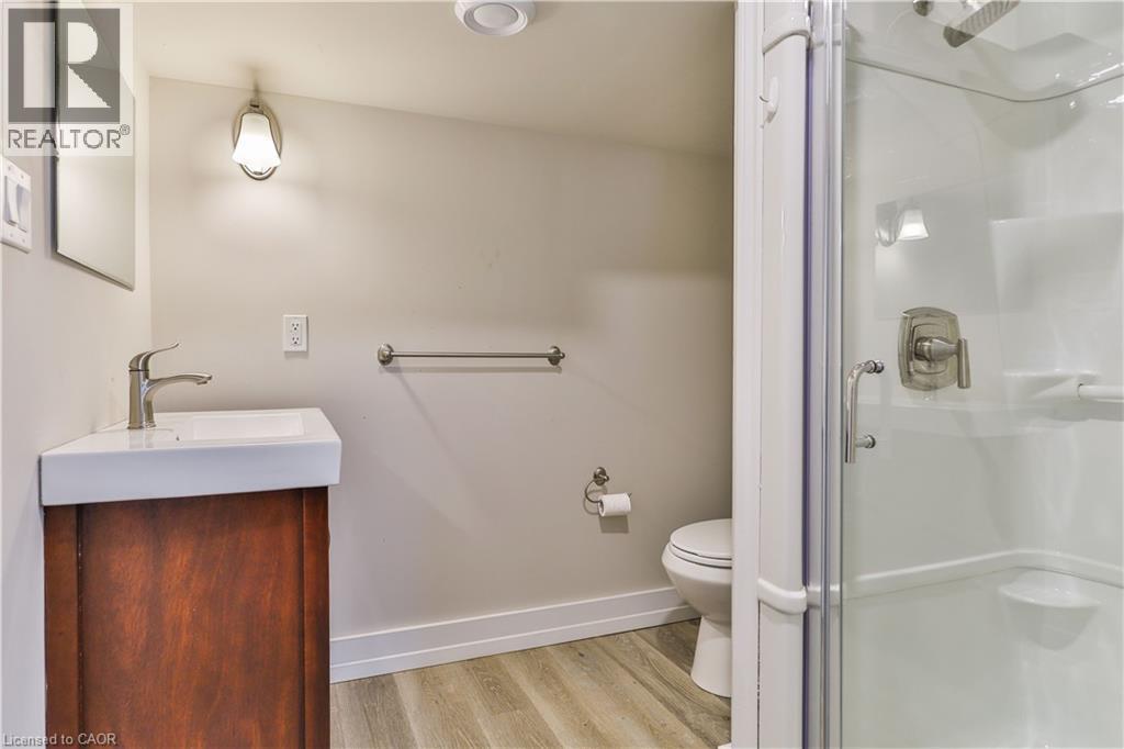 Three-piece bathroom featuring a corner vanity with a rectangular basin, glass-enclosed shower, wood-finish flooring, and a recessed ceiling light - 38 Dunkirk Drive Unit# B, Hamilton, ON - Indoor Photo Showing Bathroom